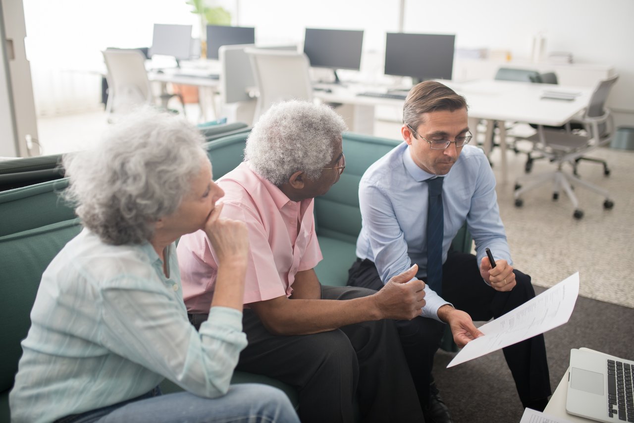 Crafting Captivating Headlines: Your awesome post title goes here Business professional consults elderly clients in an office setting. Collaborative discussion, paperwork visible.